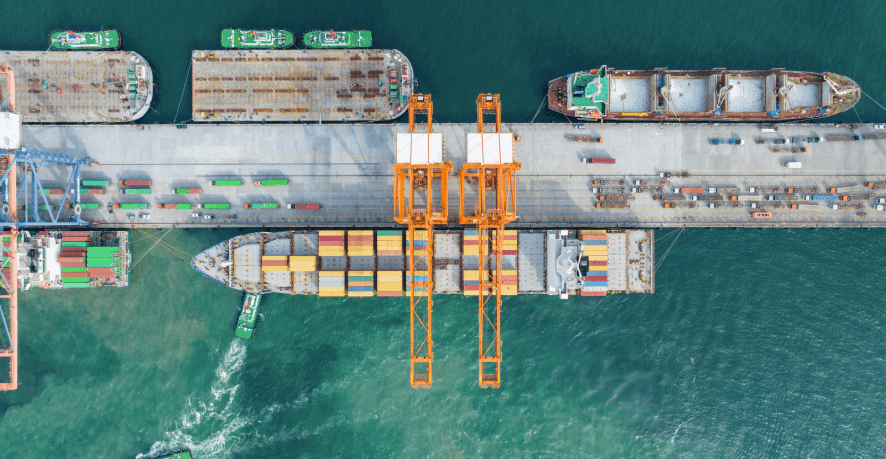 aerial view of a container port with cargo ships berthed alongside gantry cranes